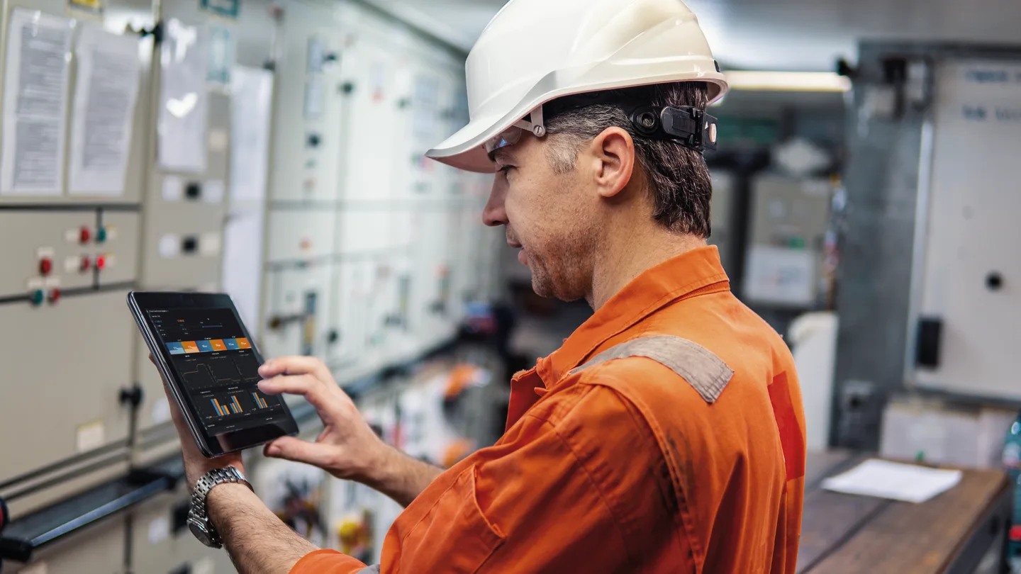 technician-in-a-control-room-on-a-ship-looking-on-an-ipad-with-ecomate-screen.webp